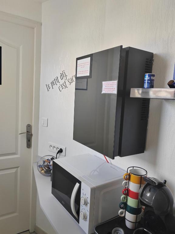 un four micro-ondes sur un comptoir dans une cuisine dans l'établissement L'Escale, chambres chez l'habitant, au Mans