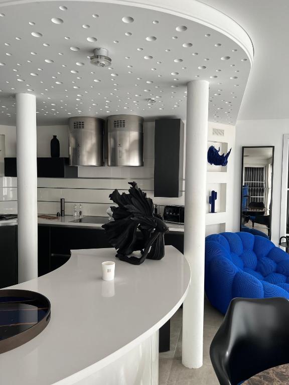 une cuisine avec une table blanche et une chaise bleue dans l'établissement 100m2 de paradis en total vue Mer, à Saint-Georges-de-Didonne