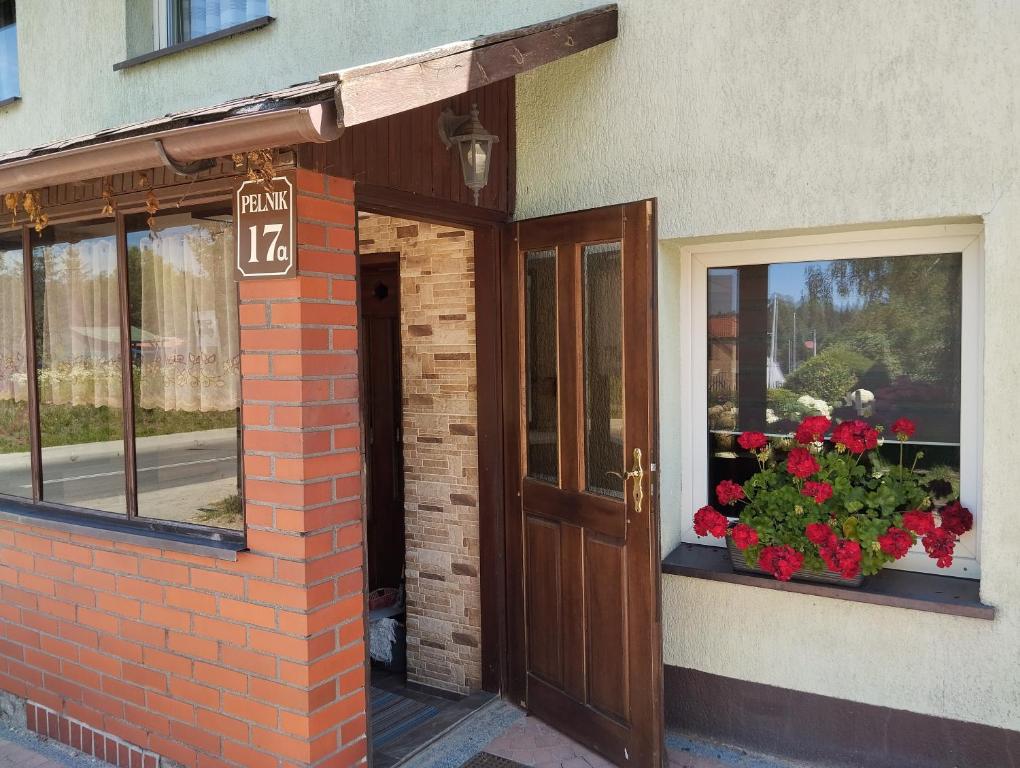a building with a door and flowers in a window at Green Hous agroturystyka in Pelnik