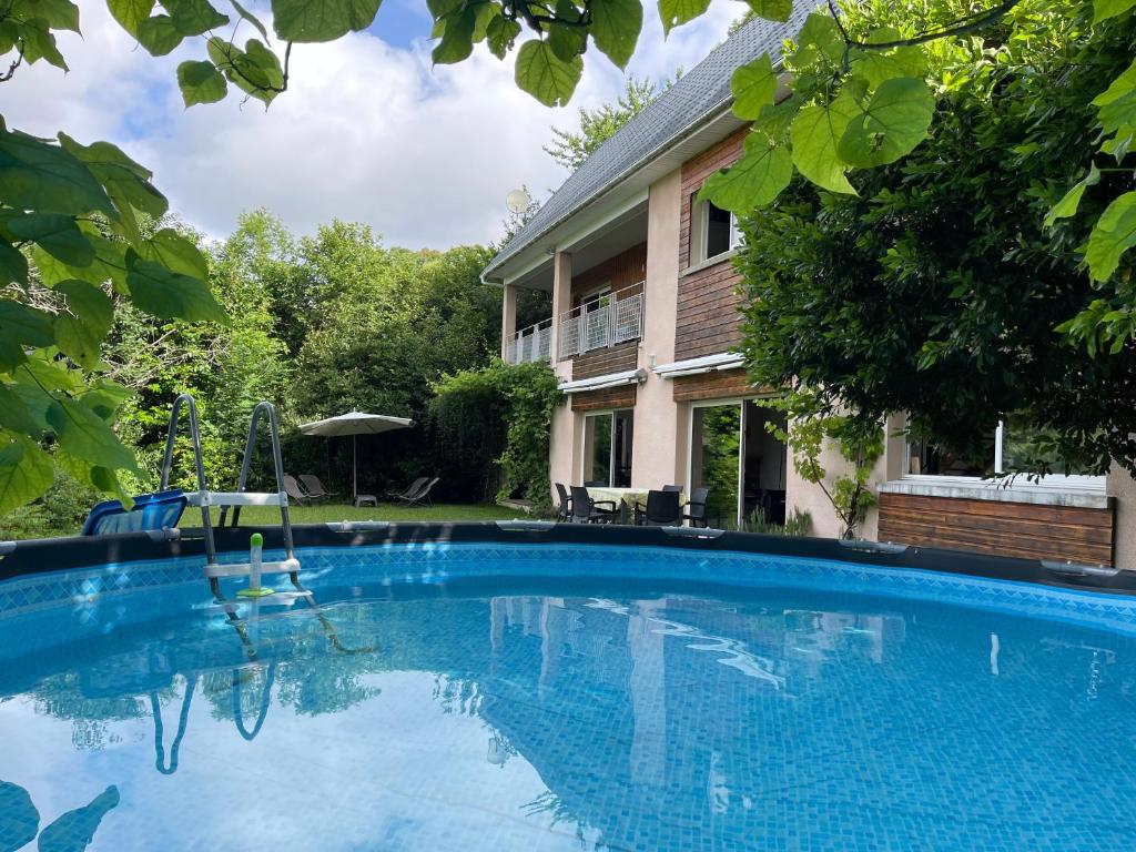 une grande piscine bleue devant une maison dans l'établissement Indoor-Outdoor Villa with Panoramic Mountain Views Near Pyrenees Hikes & Atlantic Beaches, à Espoey