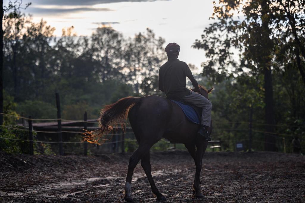 a man riding a horse on a dirt road at Saraca Resort & Spa Corbett in Garjia