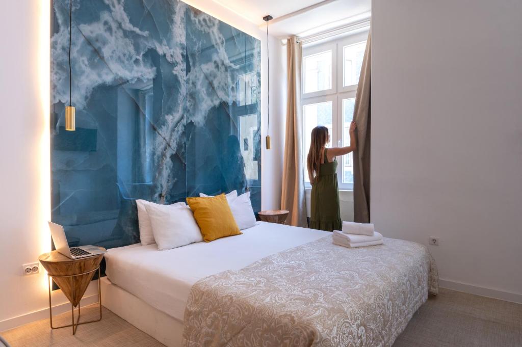 Una donna sta guardando fuori dalla finestra di una camera da letto di Lisbon Studios a Lisbona