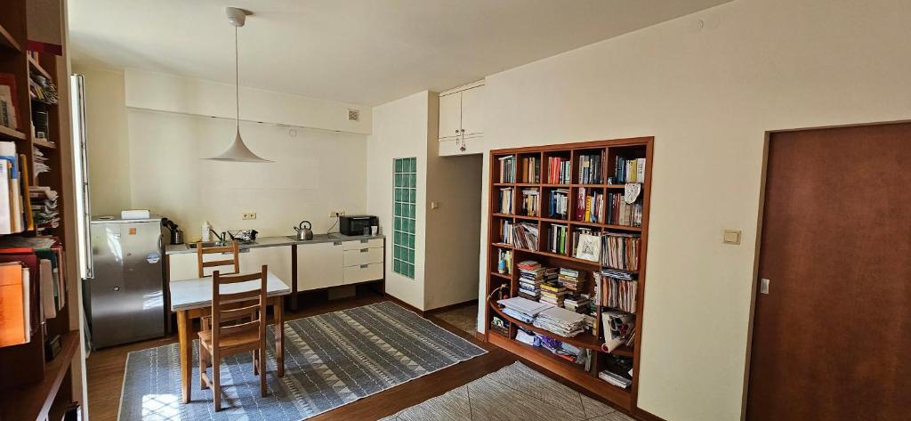 a kitchen with a refrigerator and a table and a book shelf at Nalewki Studio in the heart of Warsaw in Warsaw
