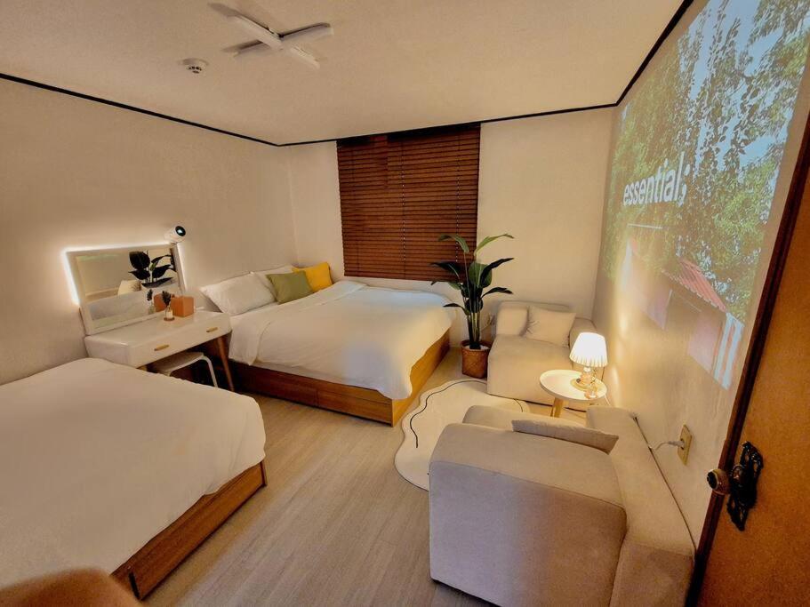 釜山にあるCozy House Busanのベッド2台と大画面スクリーンが備わるホテルルームです。