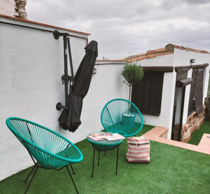two chairs and an umbrella on a yard at Casa María Rosa in Baños de la Encina