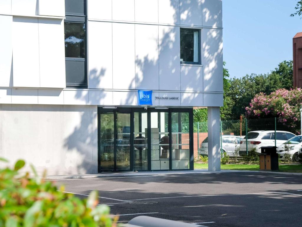 een kantoorgebouw met glazen deuren en een parkeerplaats bij ibis budget Toulouse Labège in Labège