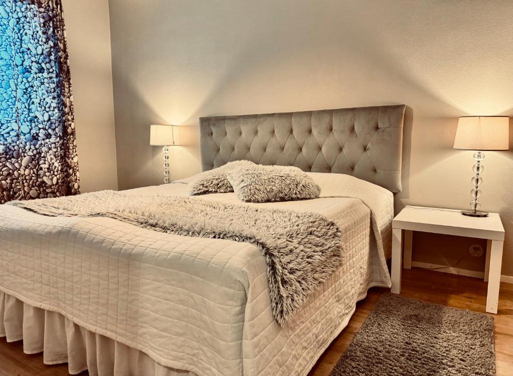 a bedroom with a white bed with a tufted headboard at FlatsinRoi Apartments in Rovaniemi