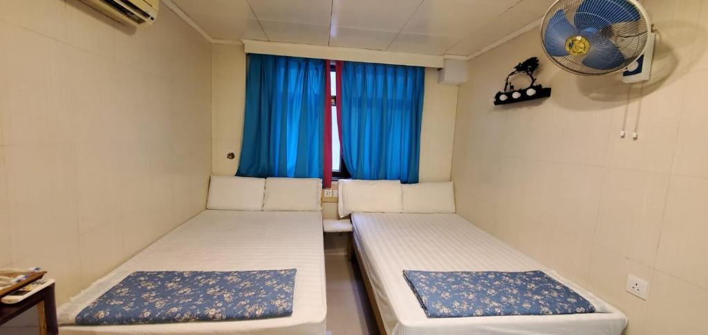 香港cebu hostel的配有窗户和风扇的客房内的两张床