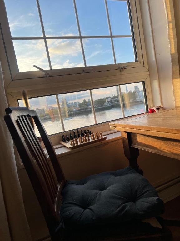 a chair sitting in front of a table with a window at Charming and Cosy Canary Wharf Room with Stunning Views in London