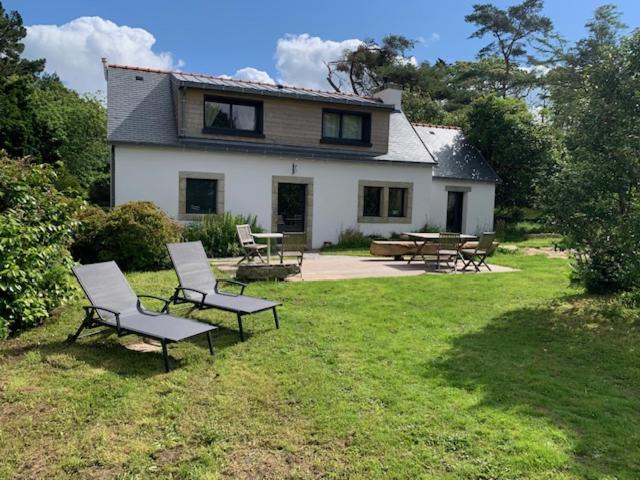 une maison avec des chaises et des tables dans une cour dans l'établissement Cottage Ty Mamm , écrin de verdure et son jardin de thé, 3étoiles, à Cast