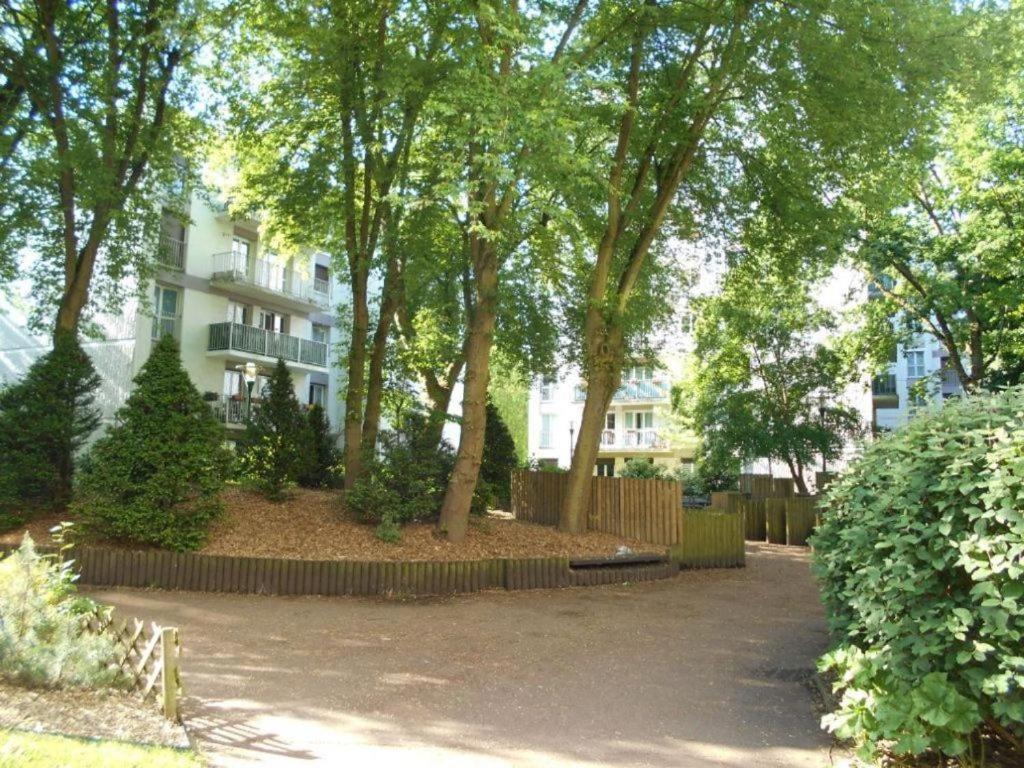 un parc avec des arbres devant un bâtiment dans l'établissement NinaParis, aux Ulis