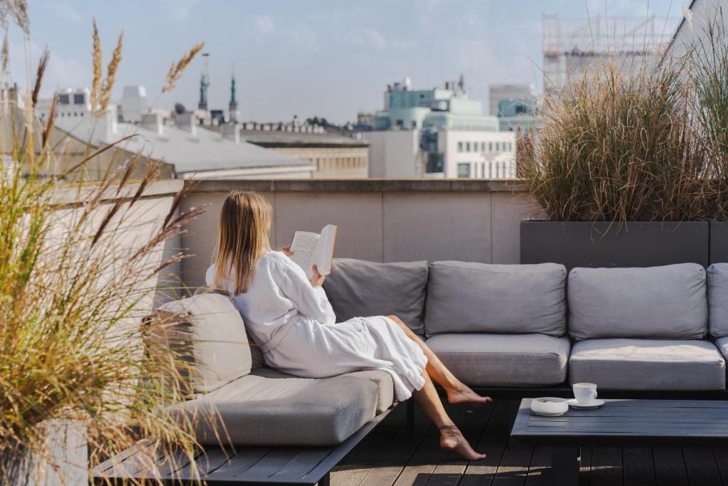 a woman sitting on a couch reading a book at H15 Boutique Hotel, Warsaw, a Member of Design Hotels in Warsaw