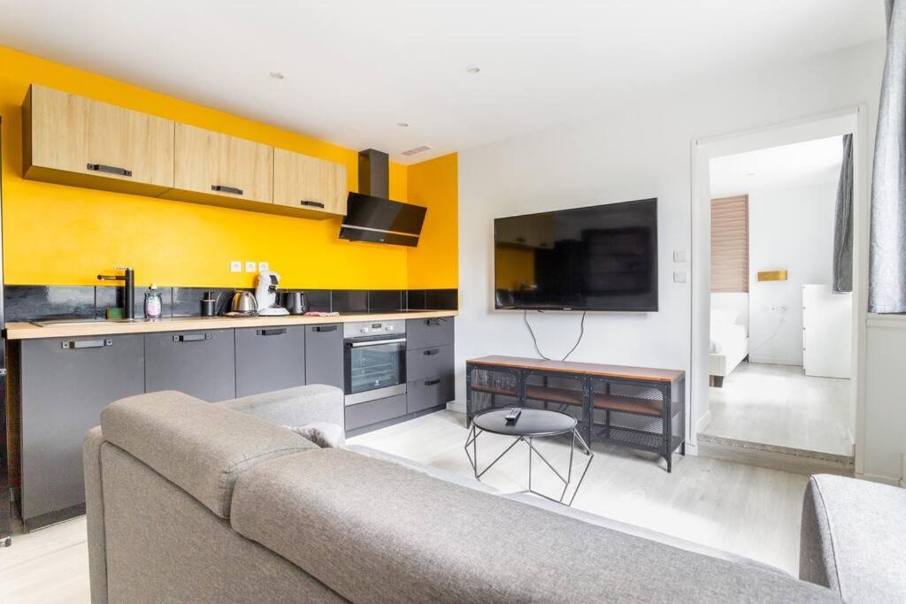 un salon avec un canapé et une cuisine dans l'établissement L'Urban chic - proche des transports, à Villeneuve d'Ascq