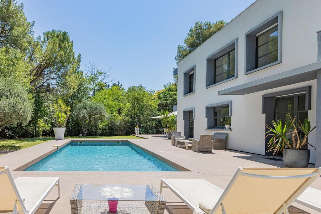 une maison avec une piscine et deux chaises dans l'établissement Villa contemporaine proche de Montpellier, à Castelnau-le-Lez