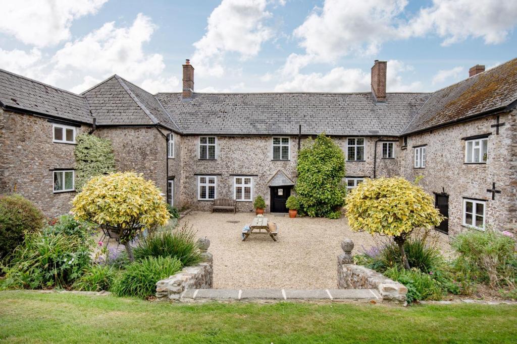 an old building with a courtyard in front of it at Sutton Barton Farmhouse in Honiton