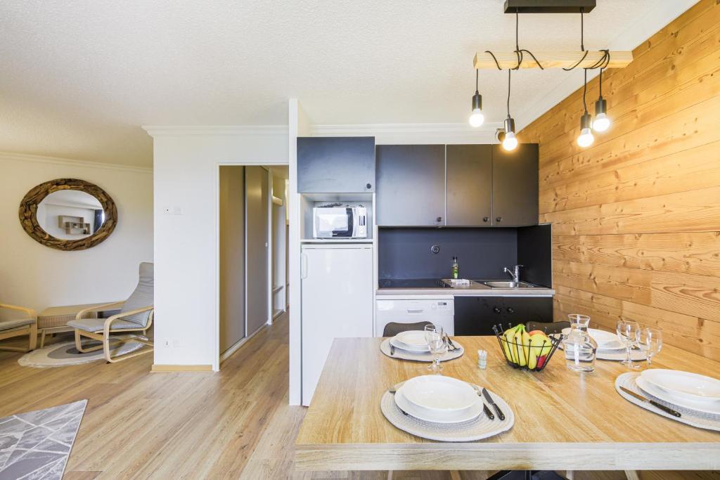 eine Küche und ein Esszimmer mit einem Tisch mit Tellern darauf in der Unterkunft Le Berger - Apt dans résidence 4 étoiles au pied des pistes in Huez