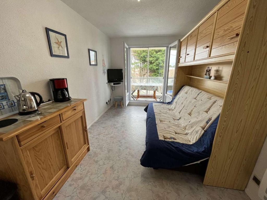 Cet appartement comprend une chambre avec un lit et une cuisine avec une fenêtre. dans l'établissement Studio cosy proche mer avec balcon, garage et commerces à 1 km - Saint-Hilaire-de-Riez - FR-1-324-516, à Saint-Hilaire-de-Riez