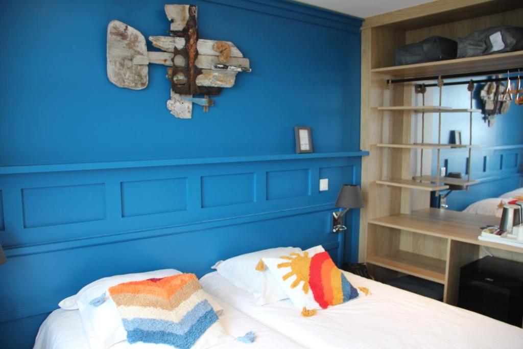 a blue room with a bed and a cross on the wall at Le Relais des Iles in Coudeville