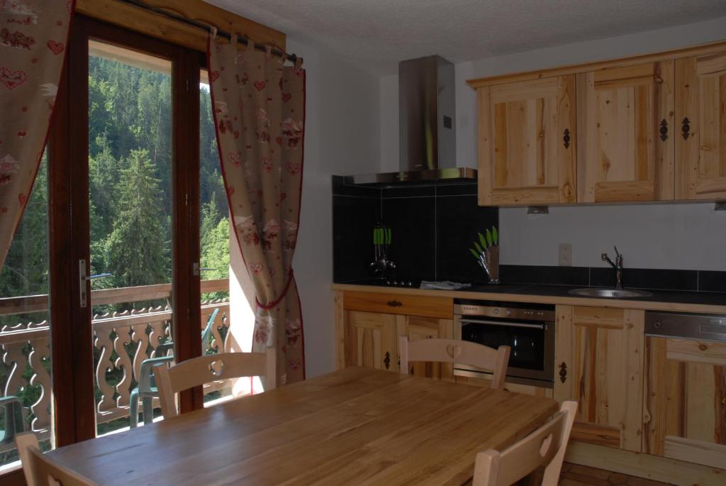 cocina con mesa de madera y balcón en Auberge des églantiers, en Flumet