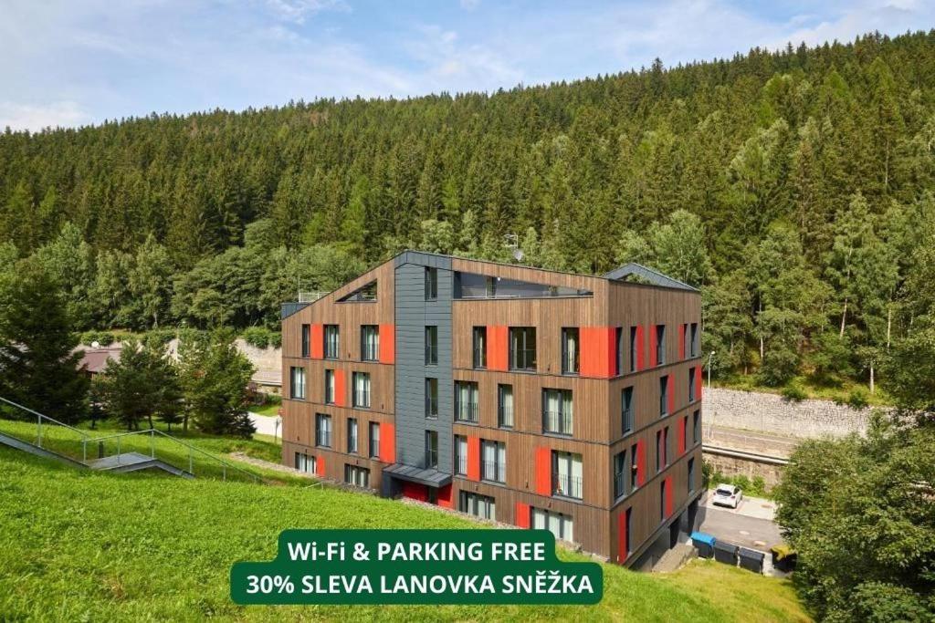 an apartment building on a hill next to a forest at Residence Vlčice in Pec pod Sněžkou