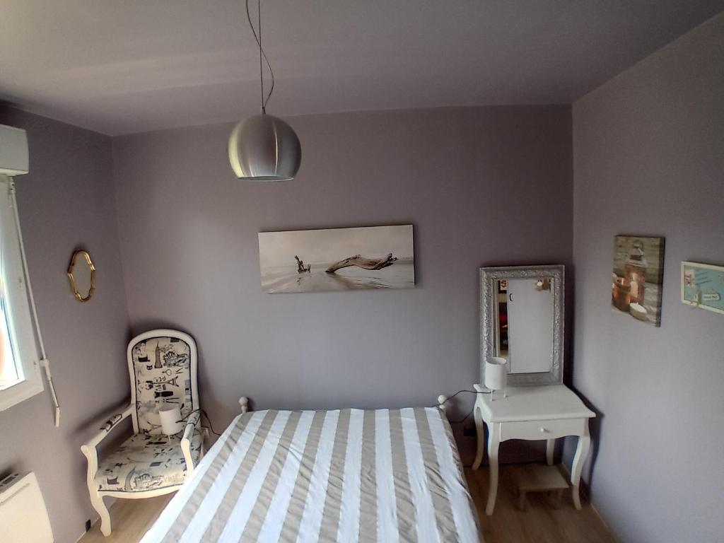 ein Schlafzimmer mit einem Bett, einem Stuhl und einem Spiegel in der Unterkunft Charmilles a 2km plage in Flocques