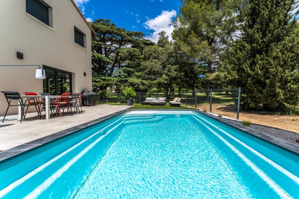 einen Pool mit einem Tisch und Stühlen neben einem Haus in der Unterkunft Vue sur parc avec pétanque, basket, clim et Tramway in Castelnau-le-Lez