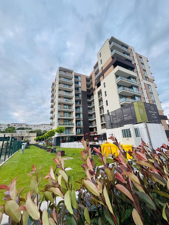 a tall apartment building with a lawn in front of it at One Apartments NordOne Iulius Town in Timişoara