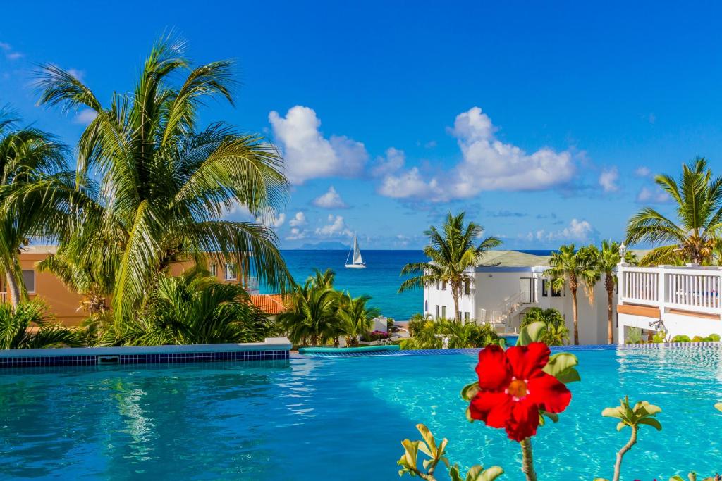 a resort swimming pool with a red flower in the foreground at La Vista Resort in Simpson Bay