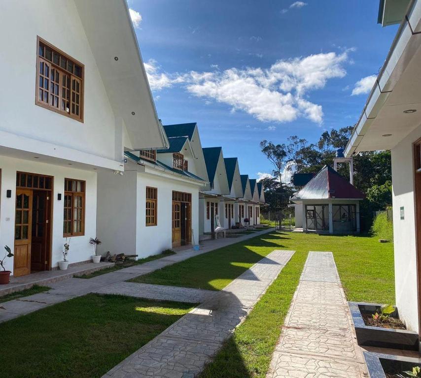 a row of white buildings with a green yard at Hahn des Felsens in Oxapampa