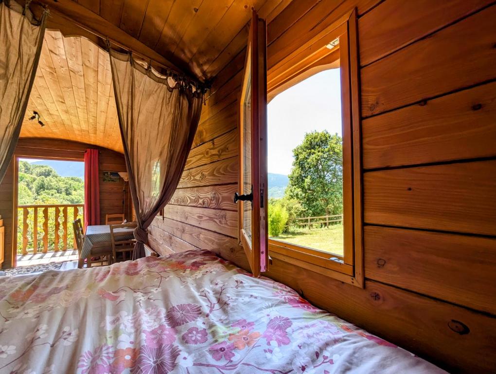 a bedroom with a bed and a large window at Roulotte du Mas Rondole in Saillagouse