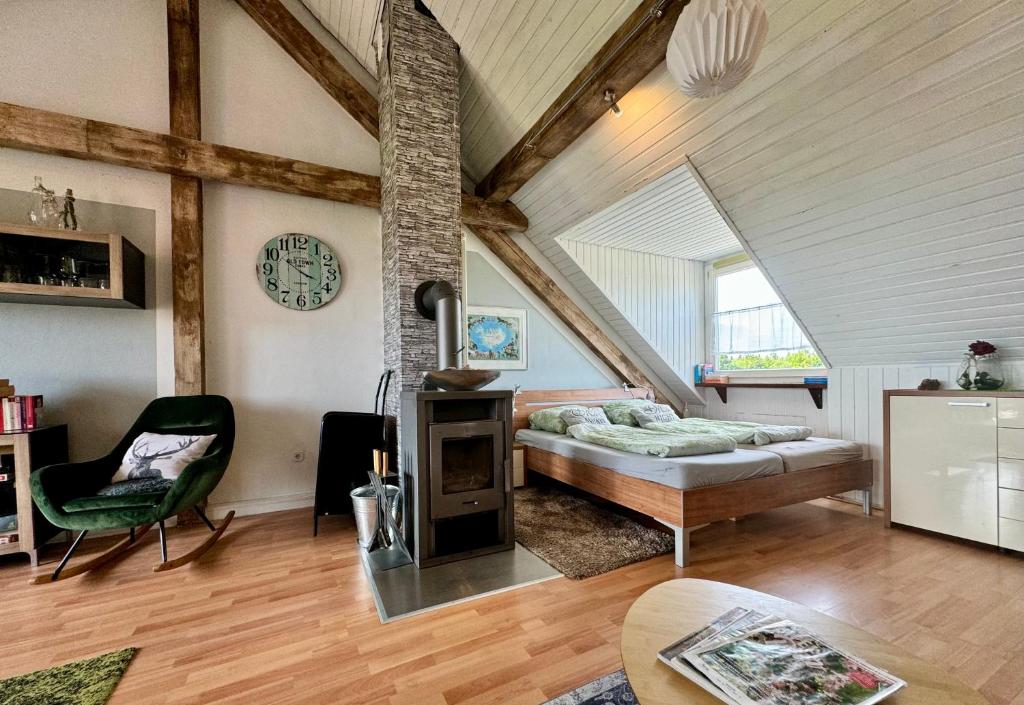 a room with a bed and a chair in a attic at Hof Vierzehnender im Hohen Venn - 70qm Fachwerk-Studio - grosses Wohn-Schlafzimmer mit Dachterrasse und Kaminofen - separate Küche - perfekt für Paare - Monschau - Eifel - Hunde willkommen - Islandpferde in Monschau