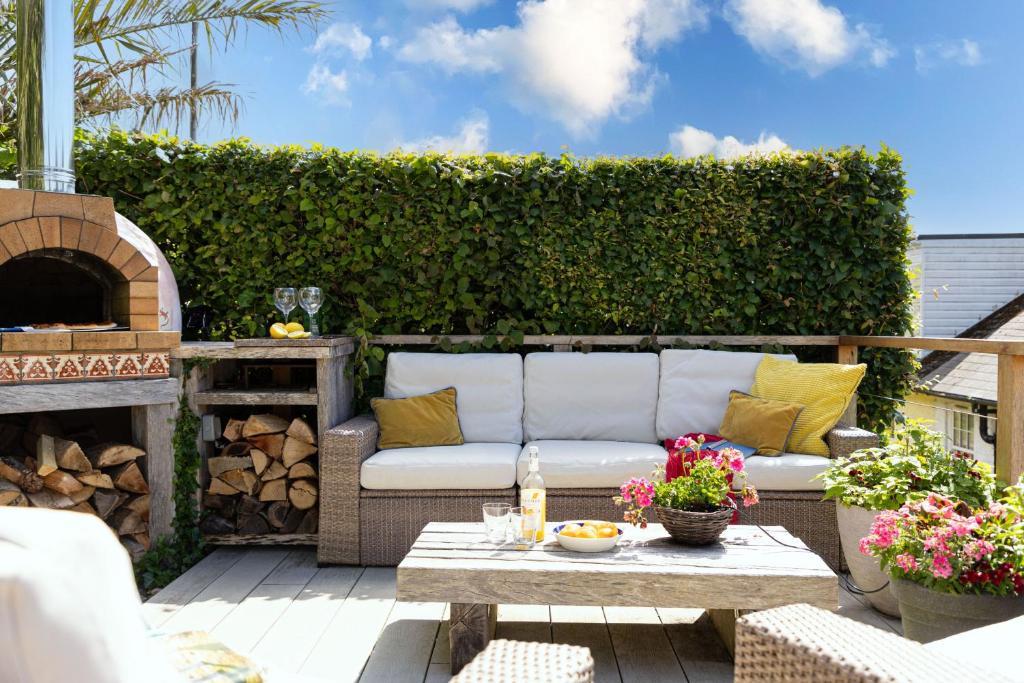 a patio with a white couch and a fireplace at The Old Shop House in Galmpton-on-the-Dart