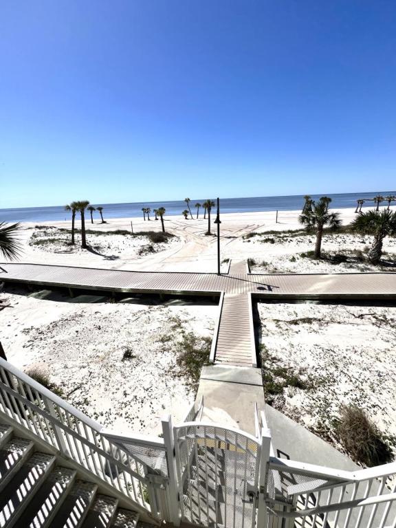 a walkway leading to a beach with palm trees at Sandy Shores Condominium in Biloxi
