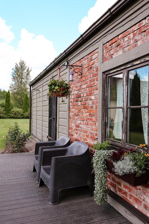 a patio with two wicker chairs and a brick building at Pirts māja in Kuldīga