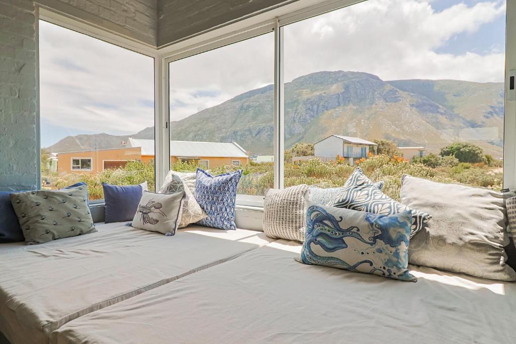 una cama con almohadas frente a una ventana en Lily House, en Bettyʼs Bay