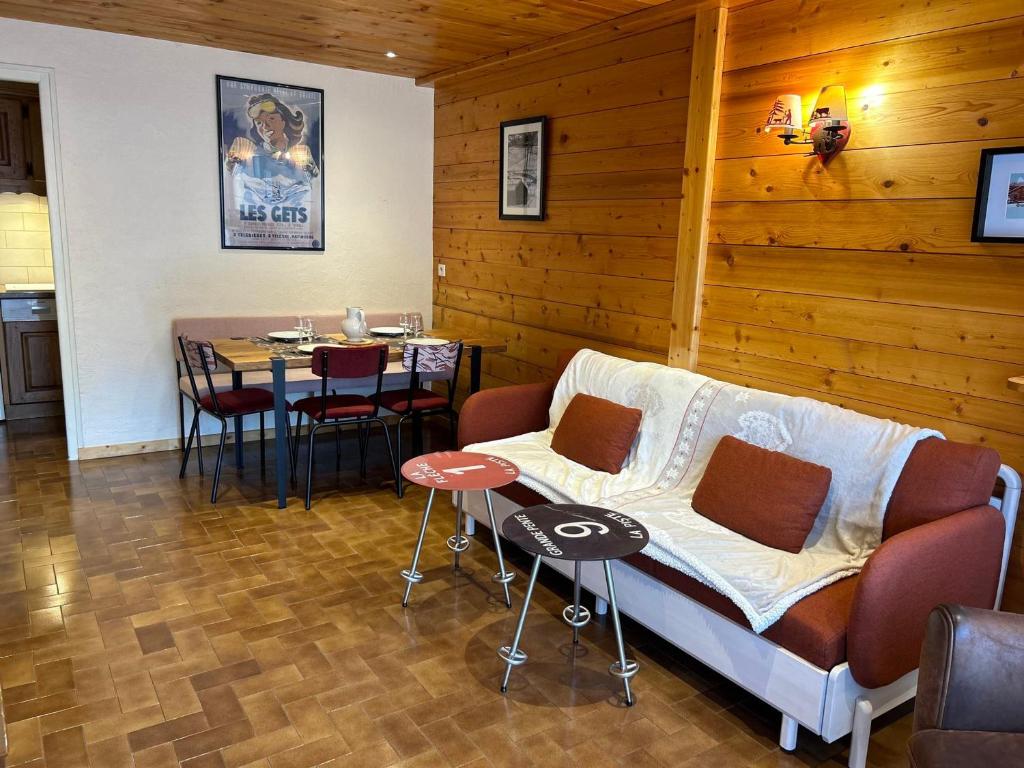 un salon avec un canapé et une table avec des chaises dans l'établissement Charmant appart 4 pers, proche pistes et centre, terrasse 30m², parking, équipements complets - FR-1-623-306, aux Gets