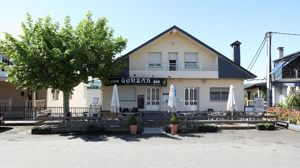 a building with tables and umbrellas in front of it at Pensión Albergue Gonzar in Portomarin