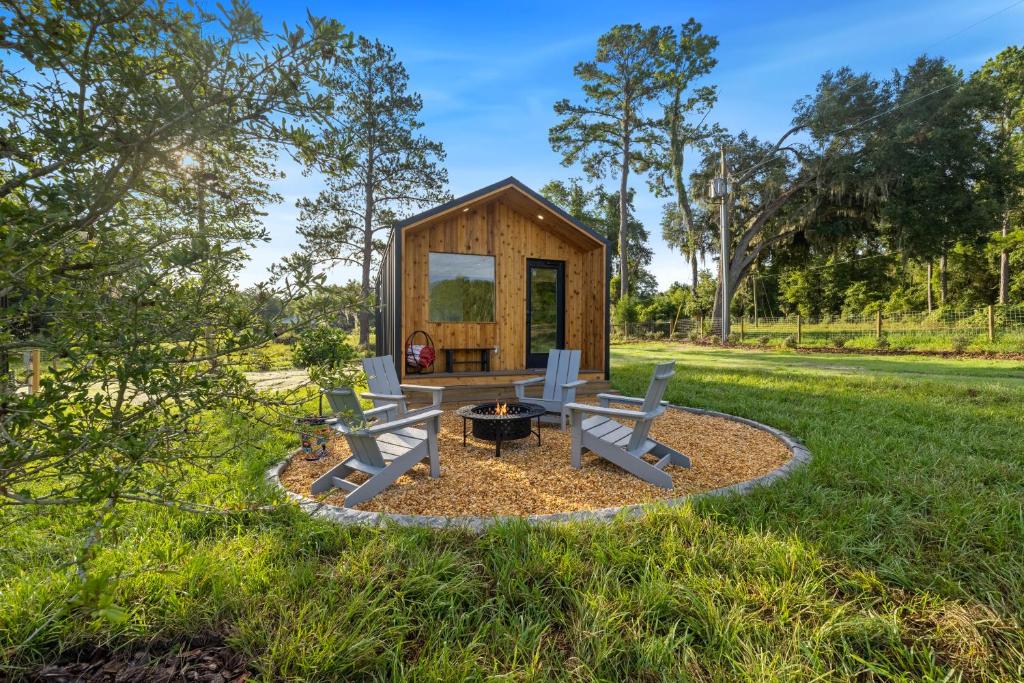 a tiny house in a park with benches and a fire pit at Vista Verde Farm Retreat - Stylish Cabins Nearby Springs in Ellisville