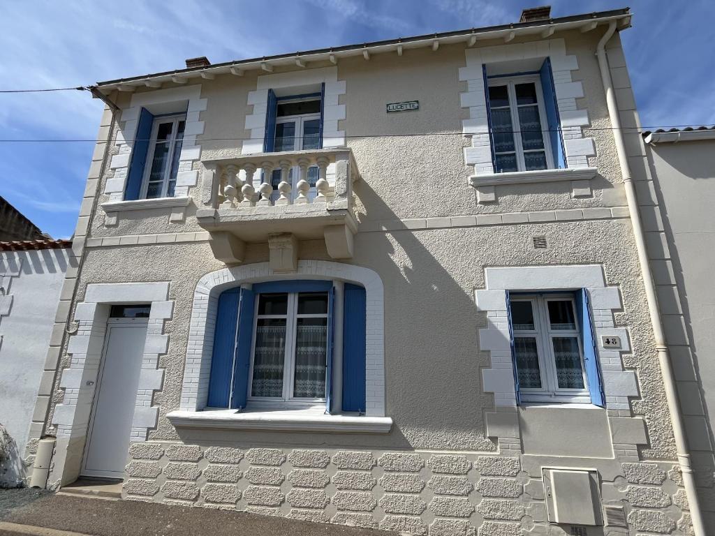 ein Gebäude mit blauen Fenstern und einem Balkon in der Unterkunft Ker Lucette in Saint-Gilles-Croix-de-Vie