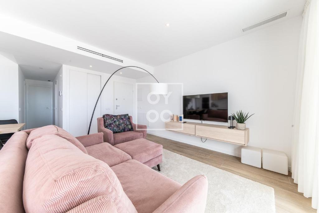 - un salon avec un canapé rose et une télévision dans l'établissement FineFleur Finestrat - see and mountain views - by OYOOSTAYS, à Finestrat