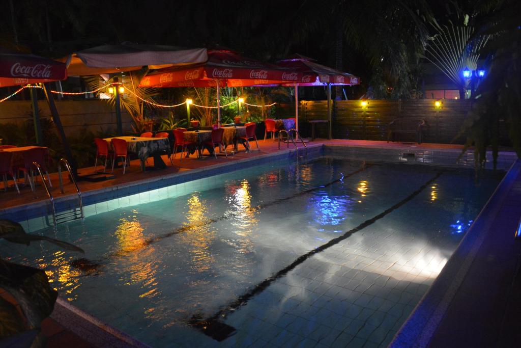 a swimming pool at night with a table and chairs at Manuela Residence in Lagos