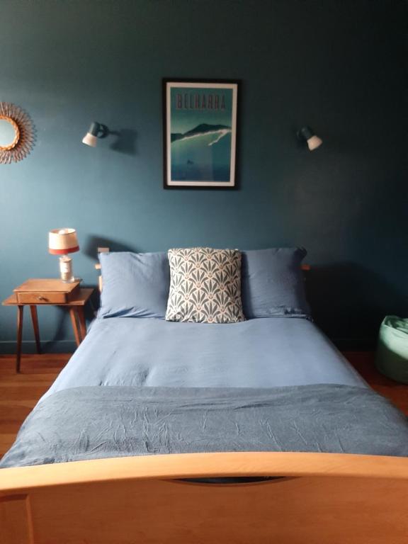 Ce lit se trouve dans une chambre dotée d'un mur bleu. dans l'établissement Chez Solange et Paul, à Mézos