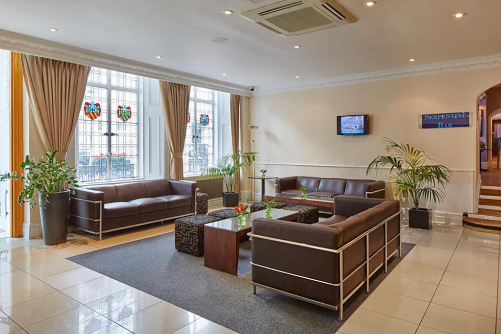 ein Wohnzimmer mit Sofas und einem Tisch in der Unterkunft Lancaster Gate Hotel in London