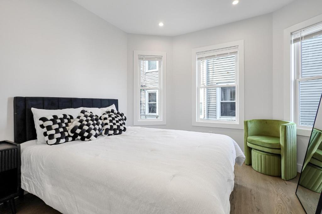 a white bedroom with a bed and a green chair at 3BR2Bth MIT Harvard TD Garden BOS 2 Parking Spaces in Somerville