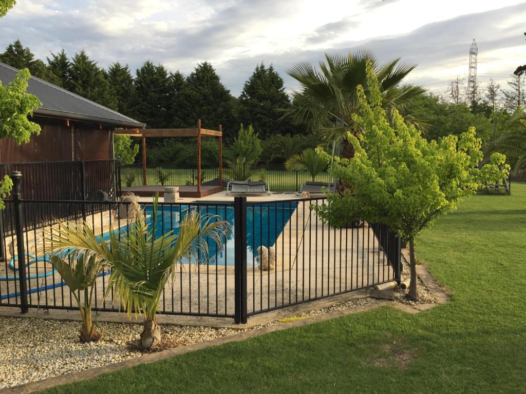 een hek met een zwembad in een tuin met bomen bij Serenity in Narre Warren North