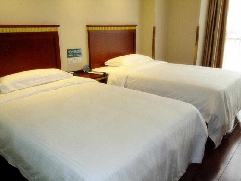 2 bedden in een hotelkamer met witte lakens bij GreenTree Inn Jiangsu Nantong Qidong Middle Heping Road Business Hotel in Qidong