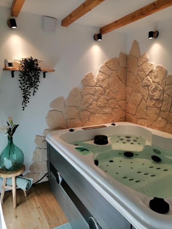une baignoire dans une pièce avec un mur en pierre dans l'établissement Parenthèse et spa à deux pas de la place Stanislas, à Malzéville