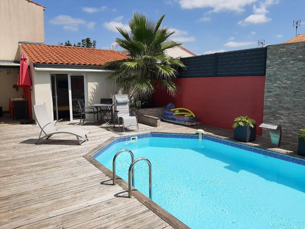 une piscine avec une terrasse et une maison dans l'établissement Studio indépendant chez l'habitant avec piscine et cuisine extérieures, à La Rochelle