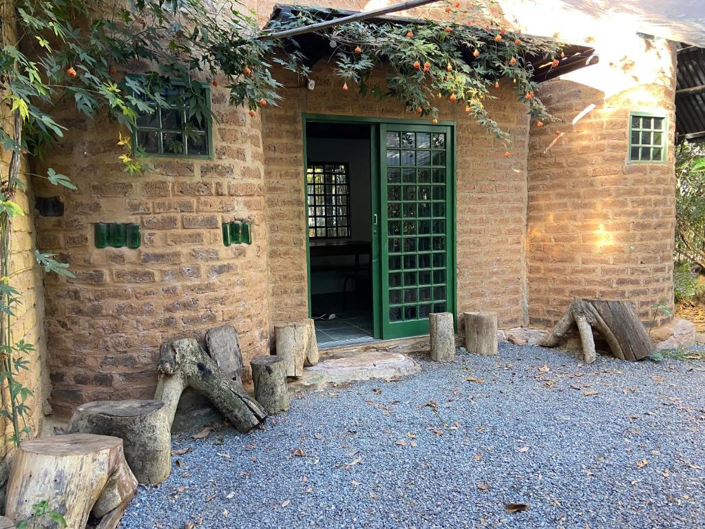 ein Gebäude mit einer grünen Tür und einigen Baumstämmen in der Unterkunft Sinta-se em casa in Alto Paraíso de Goiás