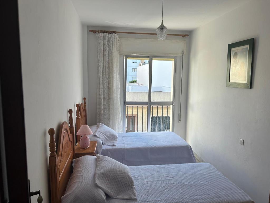 a bedroom with two beds and a window at Pisos Isla Cristina 1 in Isla Cristina